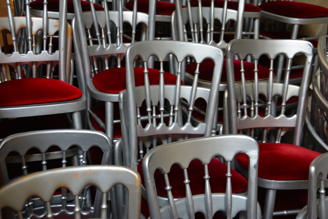 Silver stacking chairs with red padded seats stored together in event venue